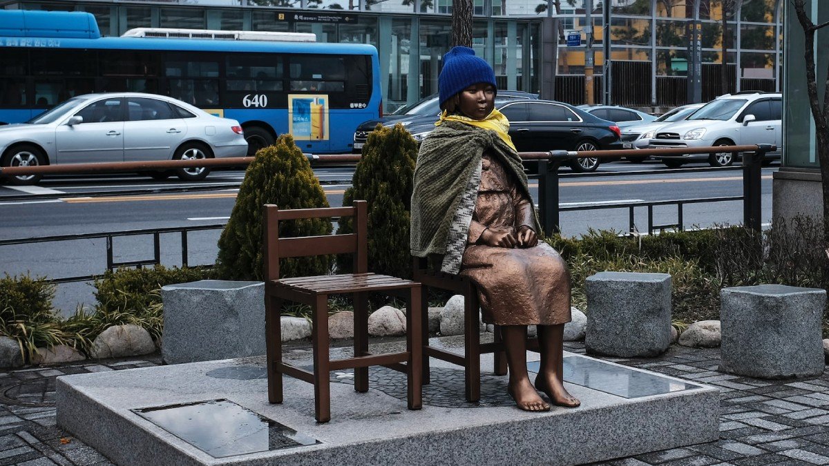 En bronsfigur av en sittande kvinna, invid gata