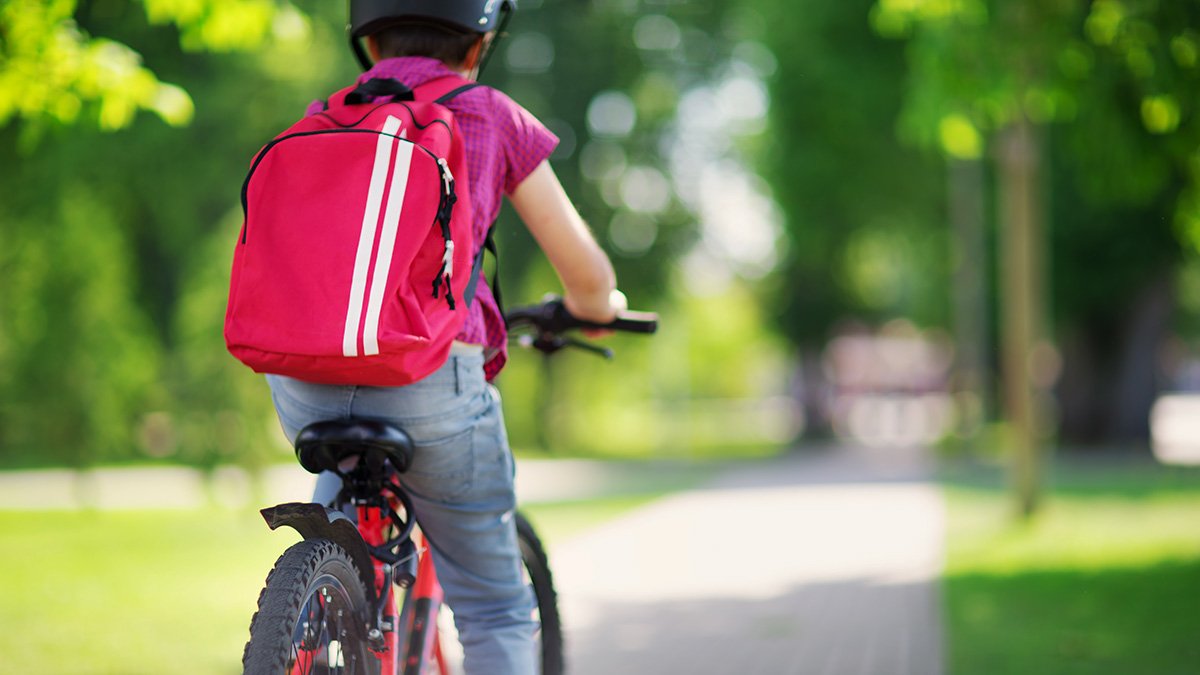 Pojke med ryggsäck cyklar