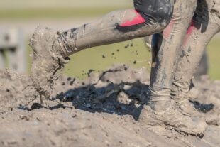 Ben och skor tillhörande två personer som springer i lera.