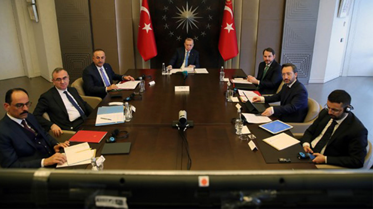 Turkiets president Erdogan sittande vid ett långt bord omgiven av rådgivare.