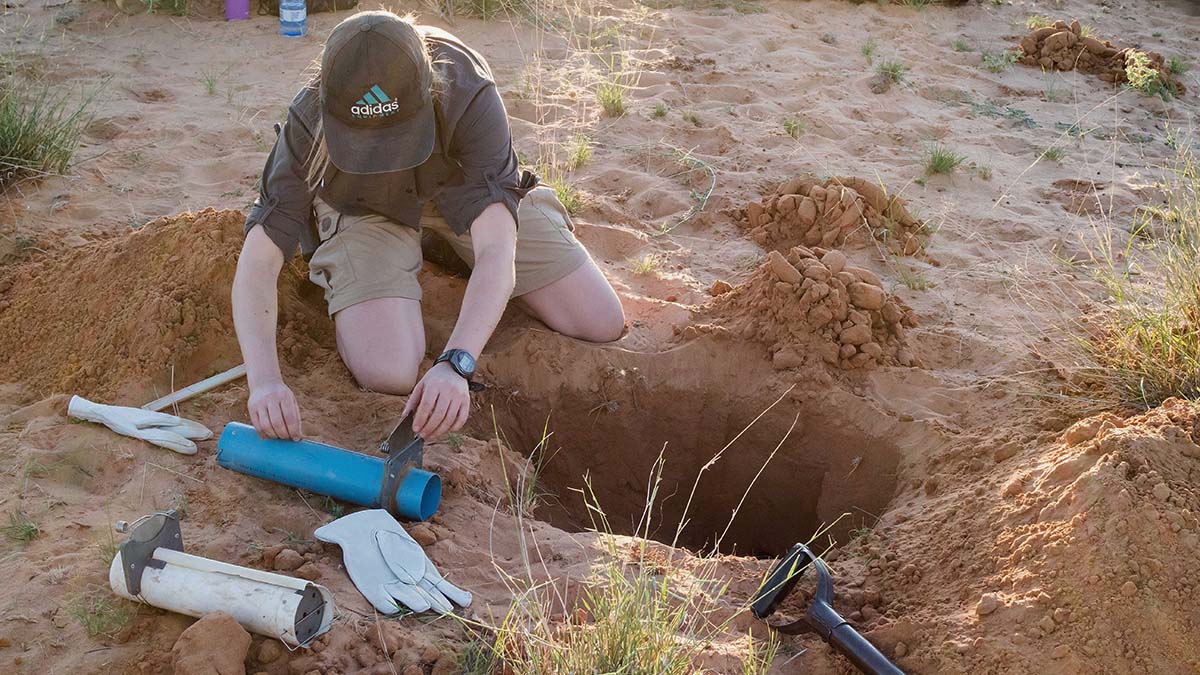 Forskare med redskap bredvid ett utgrävt hål i Kalahariöken.