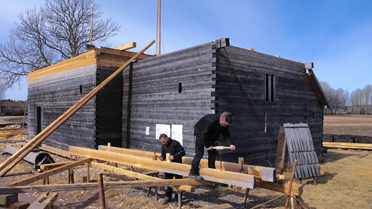 Två forskare i kulturvård bearbetar en trästock som ska ingå i bygget av Södra Råda kyrka.