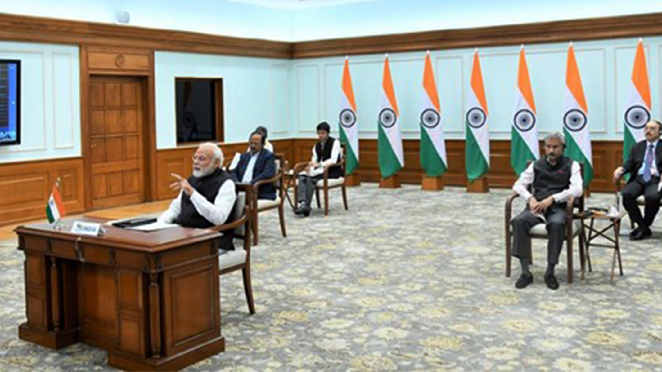 Narendra Modi, Indiens premiärminister, sitter i ett stort rum med sina medarbetare utspridda bakom sig.
