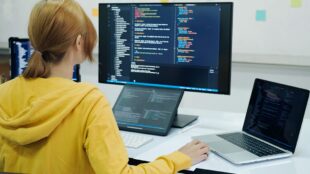 Kvinnlig programmerare framför datorskärmar