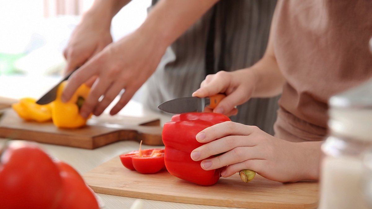 Barn och vuxen skär paprika