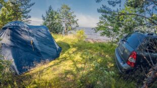 Bil parkerad intill ett tält i naturen