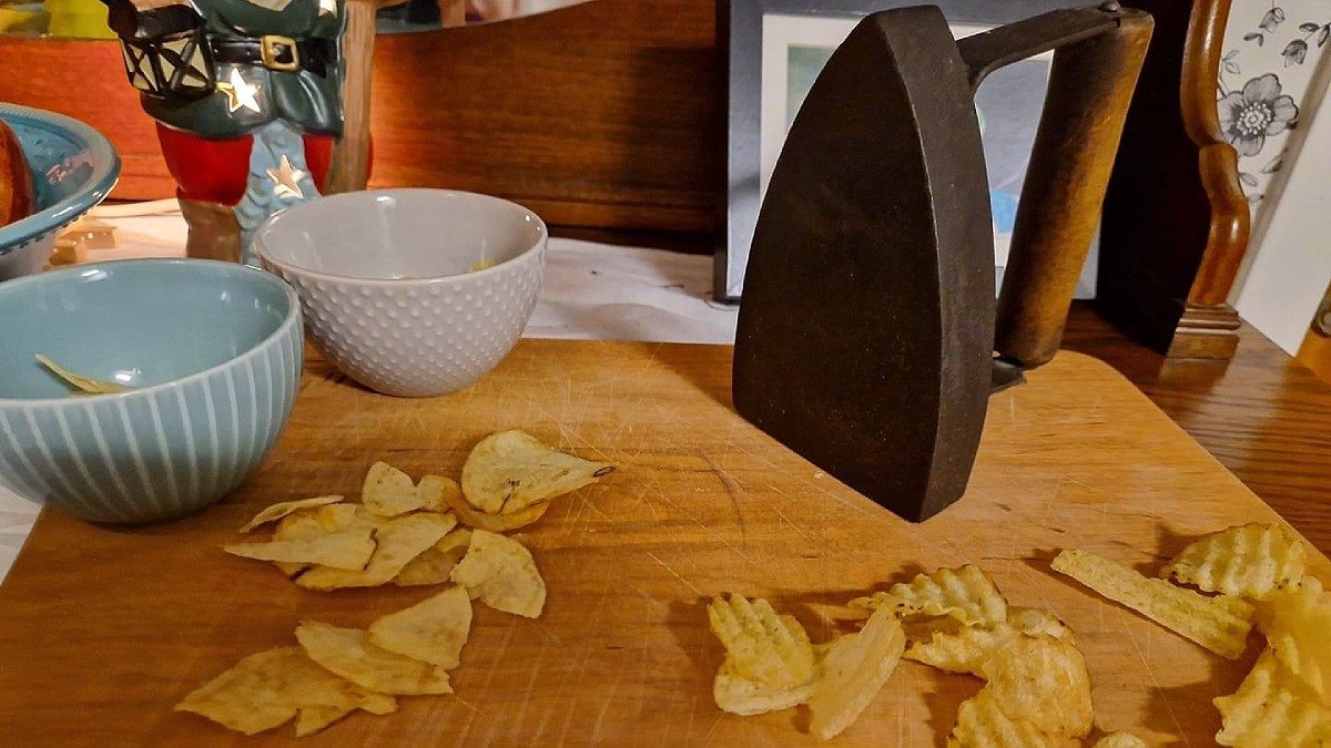 Två högar med chips samt ett gammaldags strykjärn står på ett trädbord.