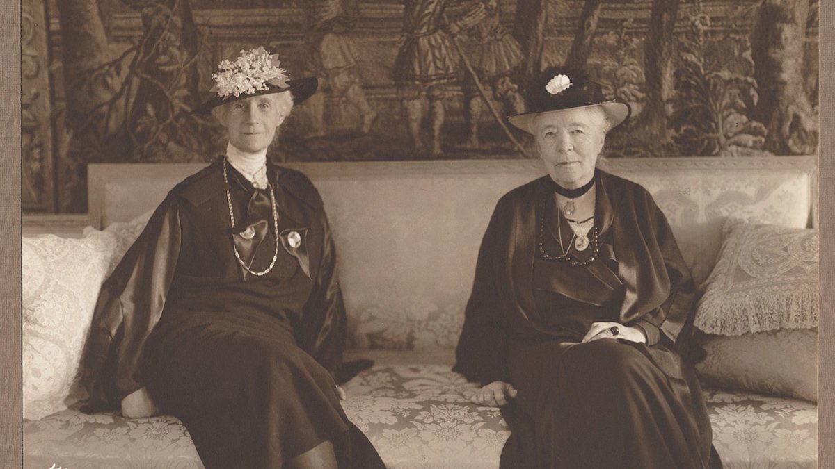 Svartvitt foto av Selma Lagerlöf och Henriette Coyet som sitter i en soffa.