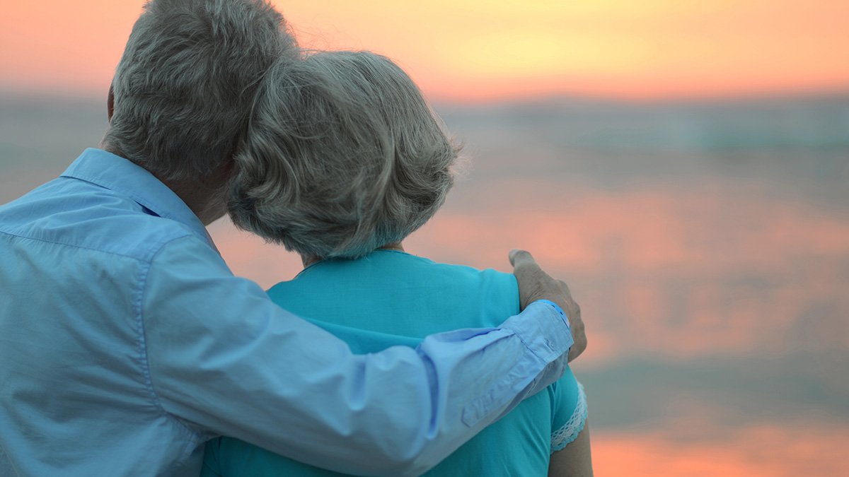 Äldre förälskat par tittar på solnedgången