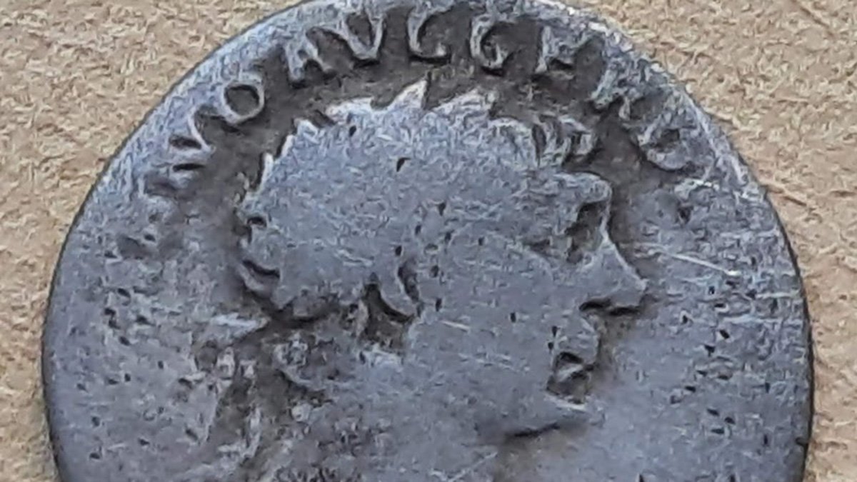 Kejsaren Trajanus i profil på myntet med en text ovanför