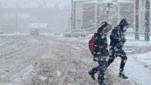 Två personer korsar en gata i snöstorm