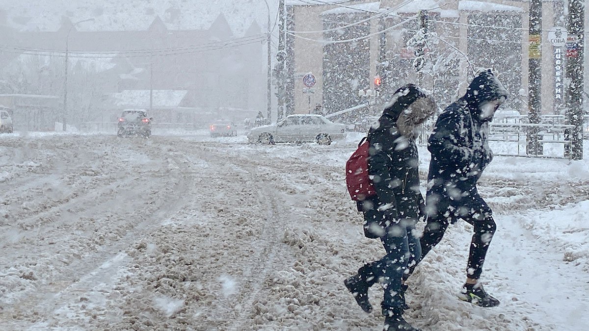 Två personer korsar en gata i snöstorm