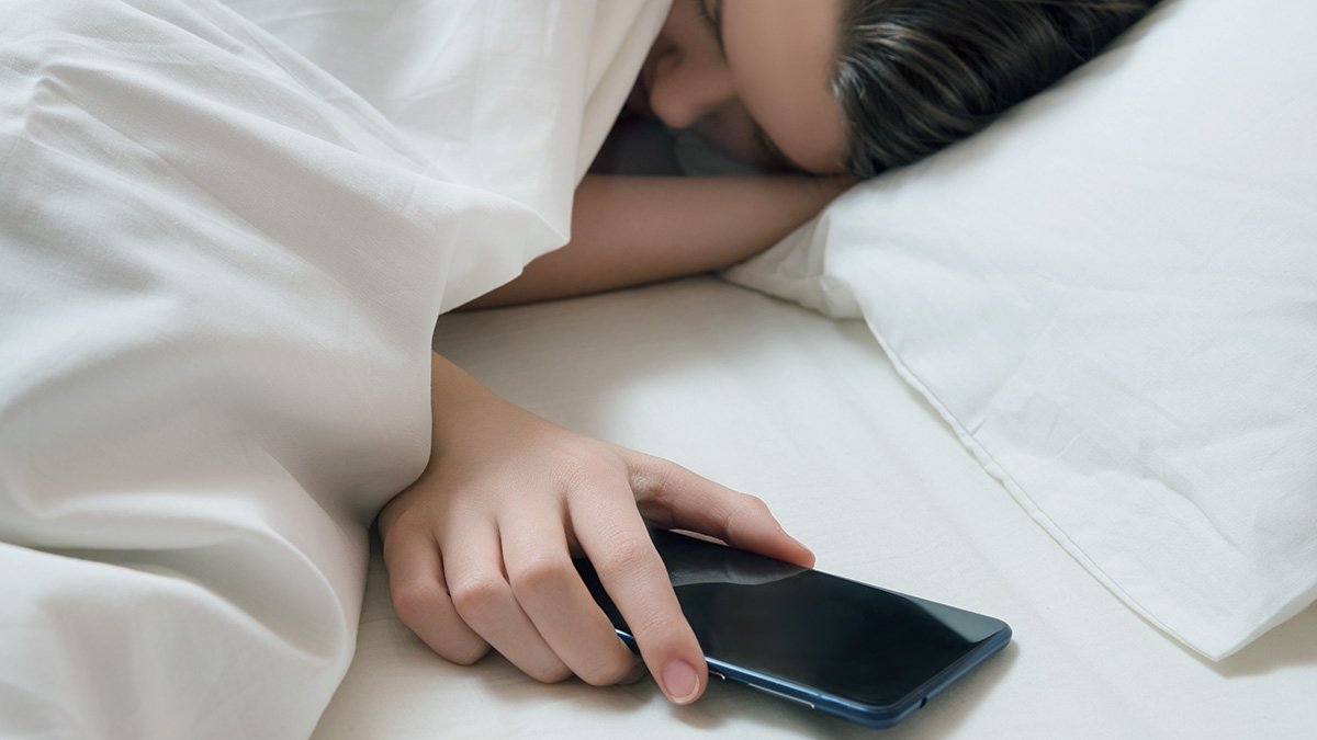 Sovande ung kvinna håller i mobiltelefon