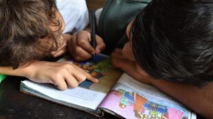 två barn läser med huvudena ihop