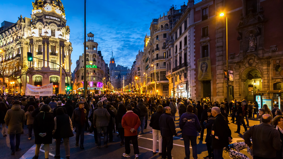 stor folksamling på gata i Madrid. Männiksor med baderoller och plakat med budskap mot bostadslöshet.