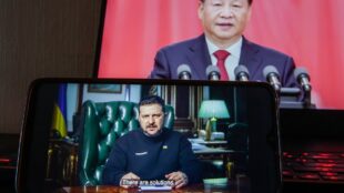 mobiltelefon i förgrunden, där Ukrainas president syns. I bakgrunden större bild på Kinas ledare.