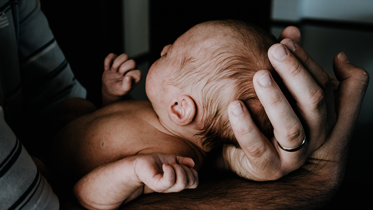 Nyfödd bebis i sin pappas händer.