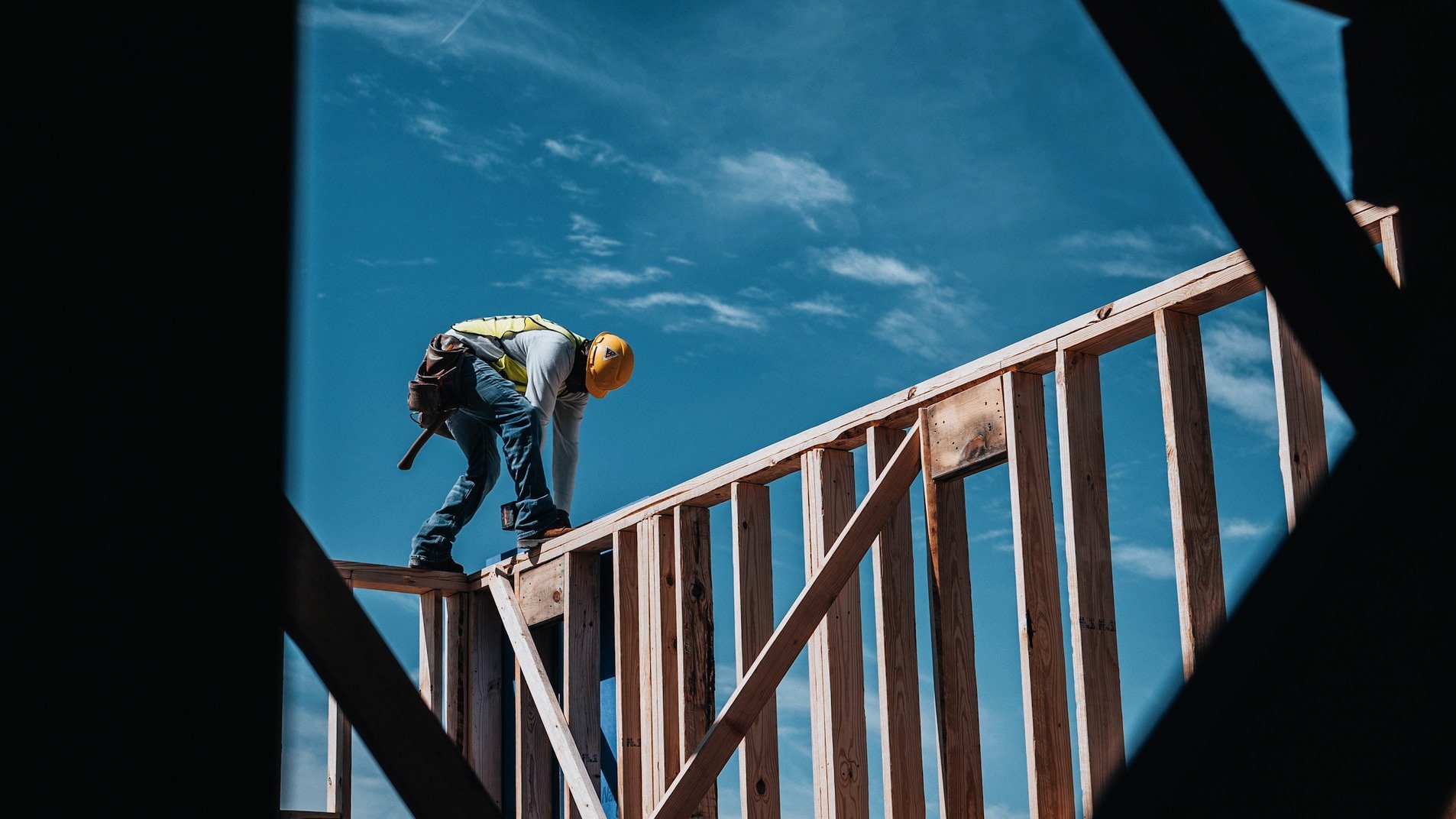Byggarbetare balanserar på träreglar på bygge, himmel i bakgrunden