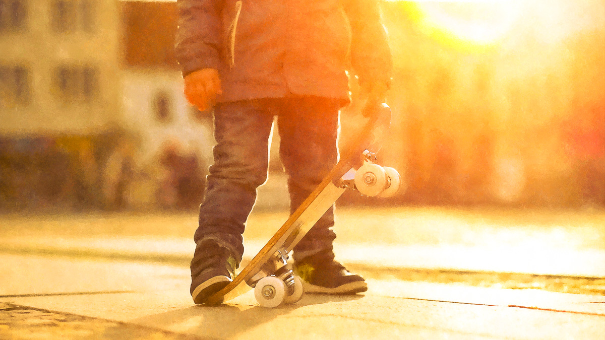 barn med skateboard, hus i bakgrunden, solnedgång