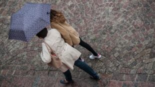 Två personer går under paraply, stadsmiljö.