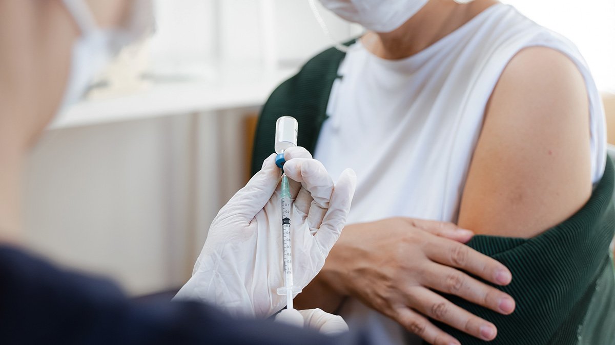 Kvinna med munskydd får vaccin