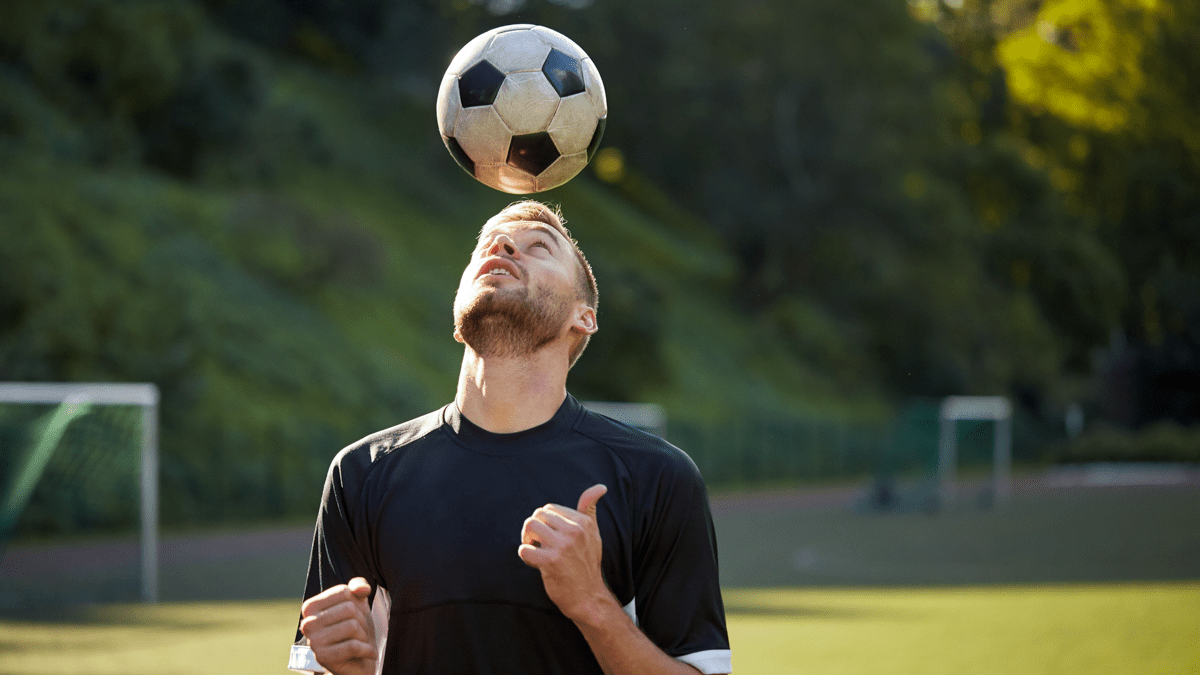 Man jonglerar en fotboll med huvudet.