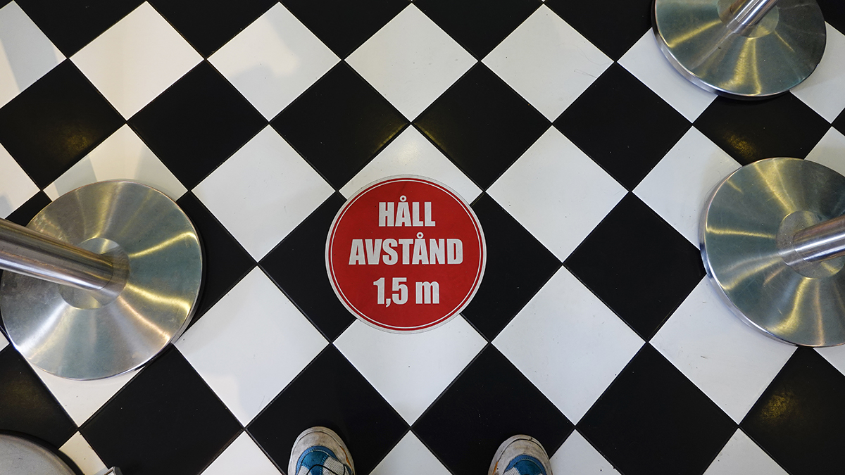 Klistermärke på golvet i en restaurang uppmanar besökare att hålla avstånd.