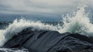 vågor slår upp mot svart klippa