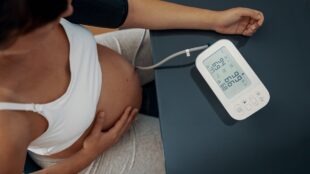 Kvinna som är gravid mäter sitt blodtryck.