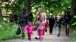 Personer från olika länder promenerar på en lummig grusväg