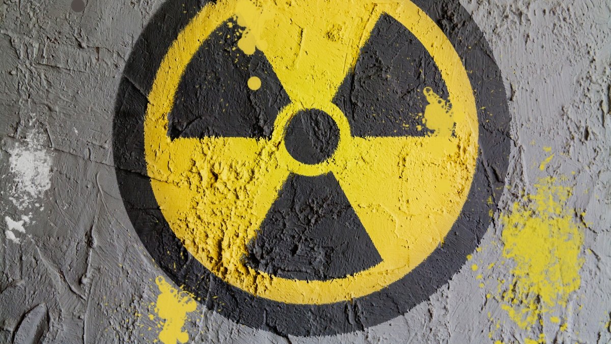 Symbolen för radioaktivitet, målad på en betongvägg i gult och svart.