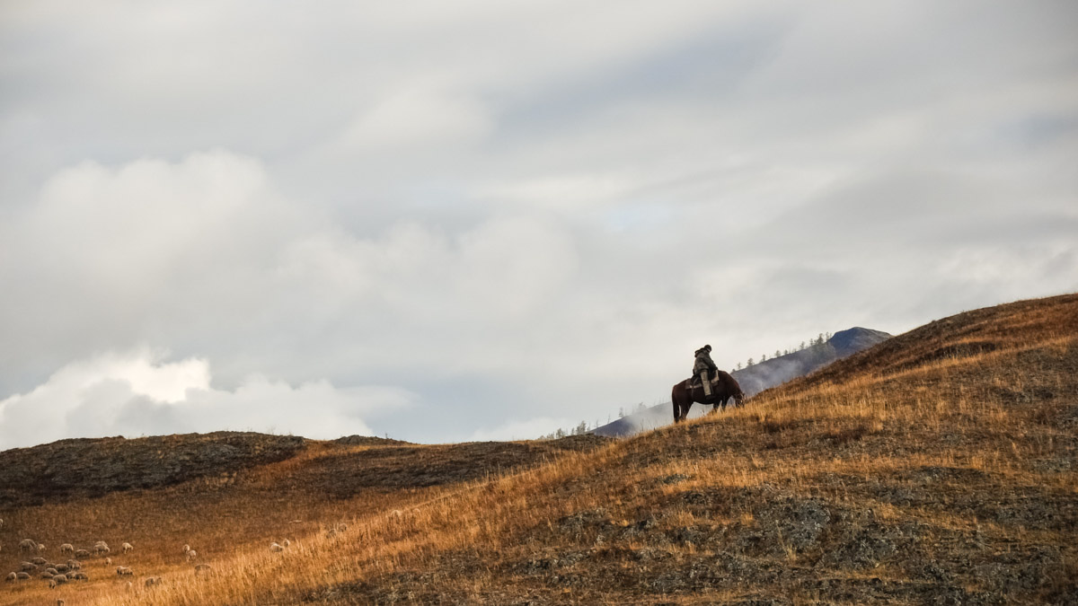 Ensam man på häst i torrt bergslandskap