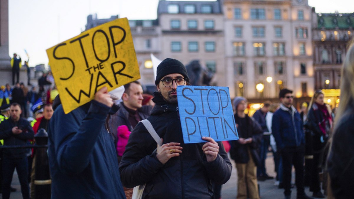 Fredsdemonstranter håller upp plakat med "Stop war" och "Stop Putin"