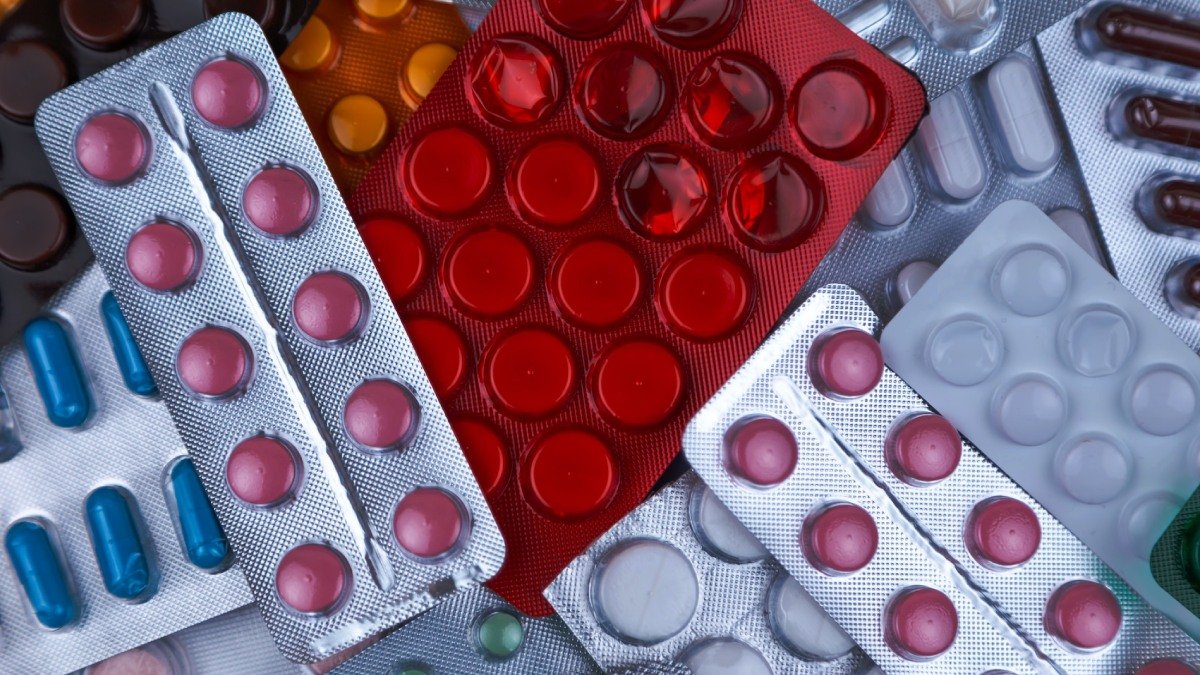 Läkemedelskartor ovanpå varandra. Röda, vita och blå piller.