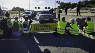 Åtta aktivister stoppar trafik på motorväg genom att sitta på rad.