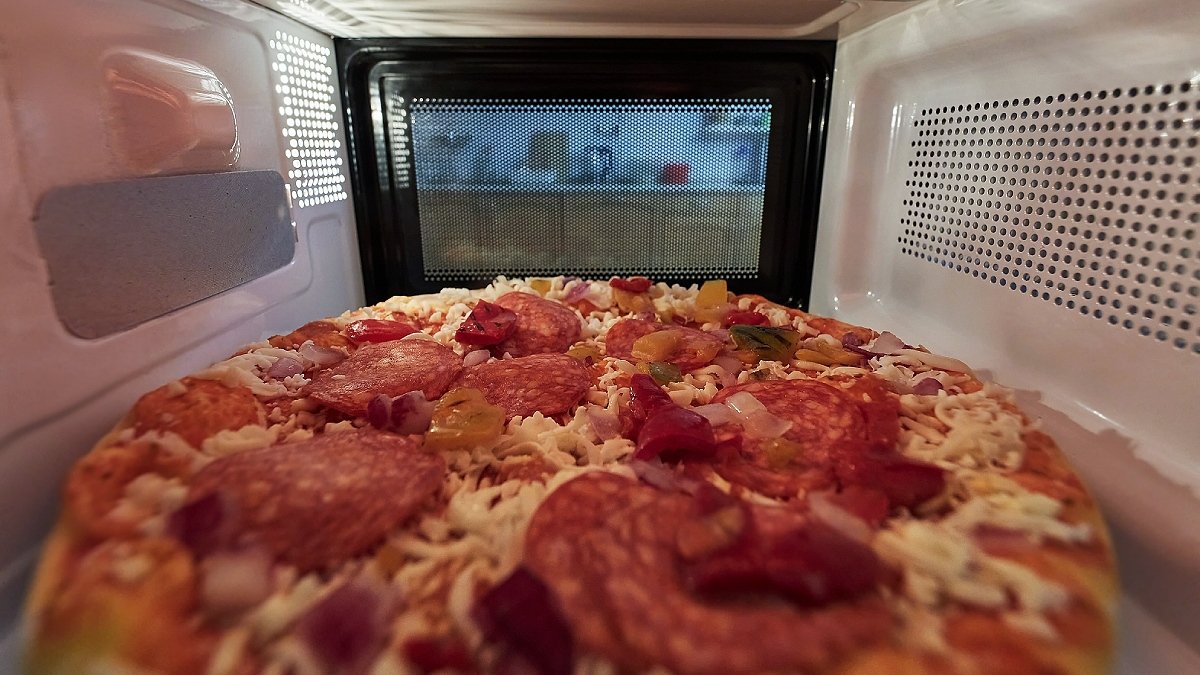 Pizza med peperoniskivor sedd inifrån mikrovågsugn.