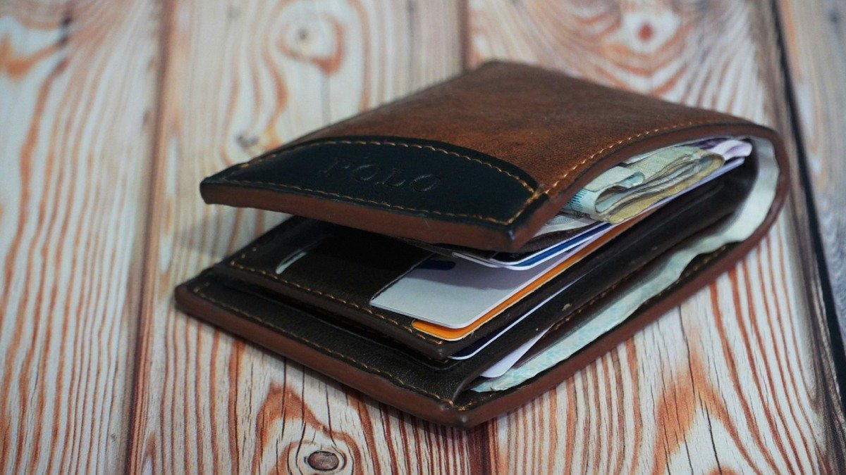 En fylld plånbok ligger på ett bord.