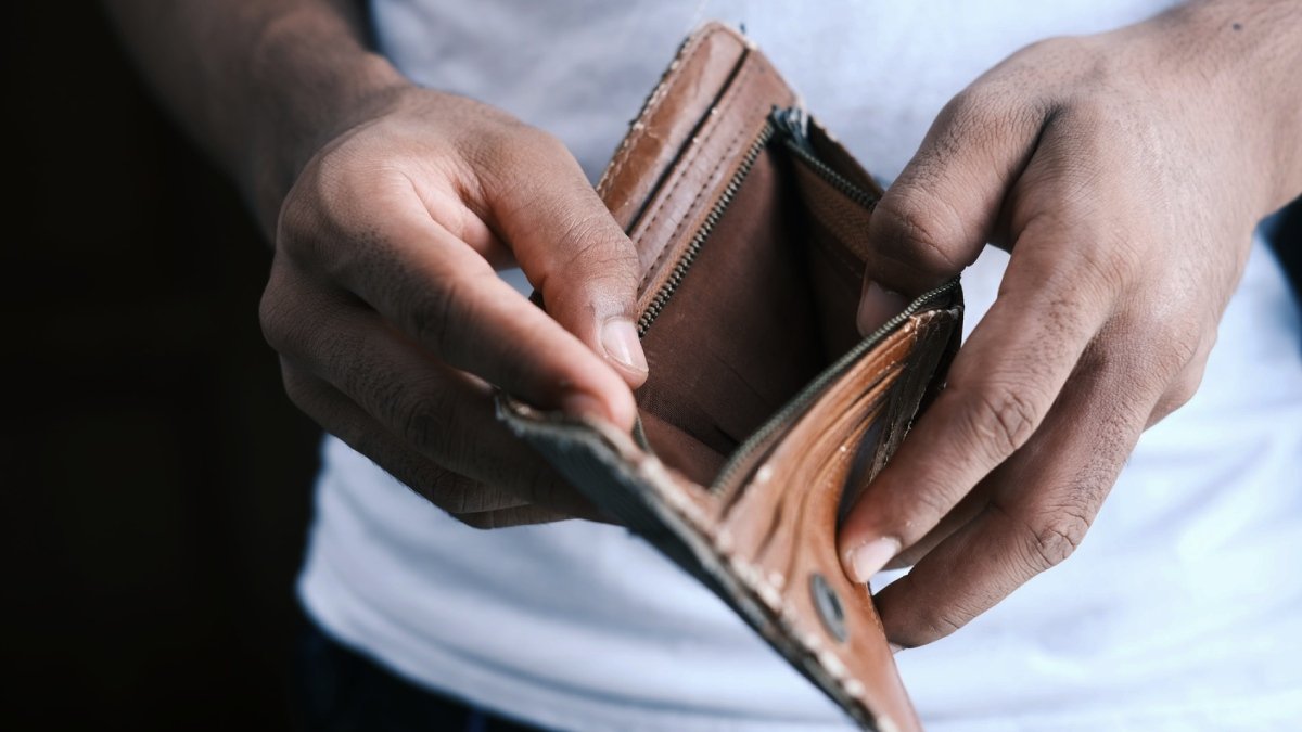 Händer som håller upp en tom brun plånbok.
