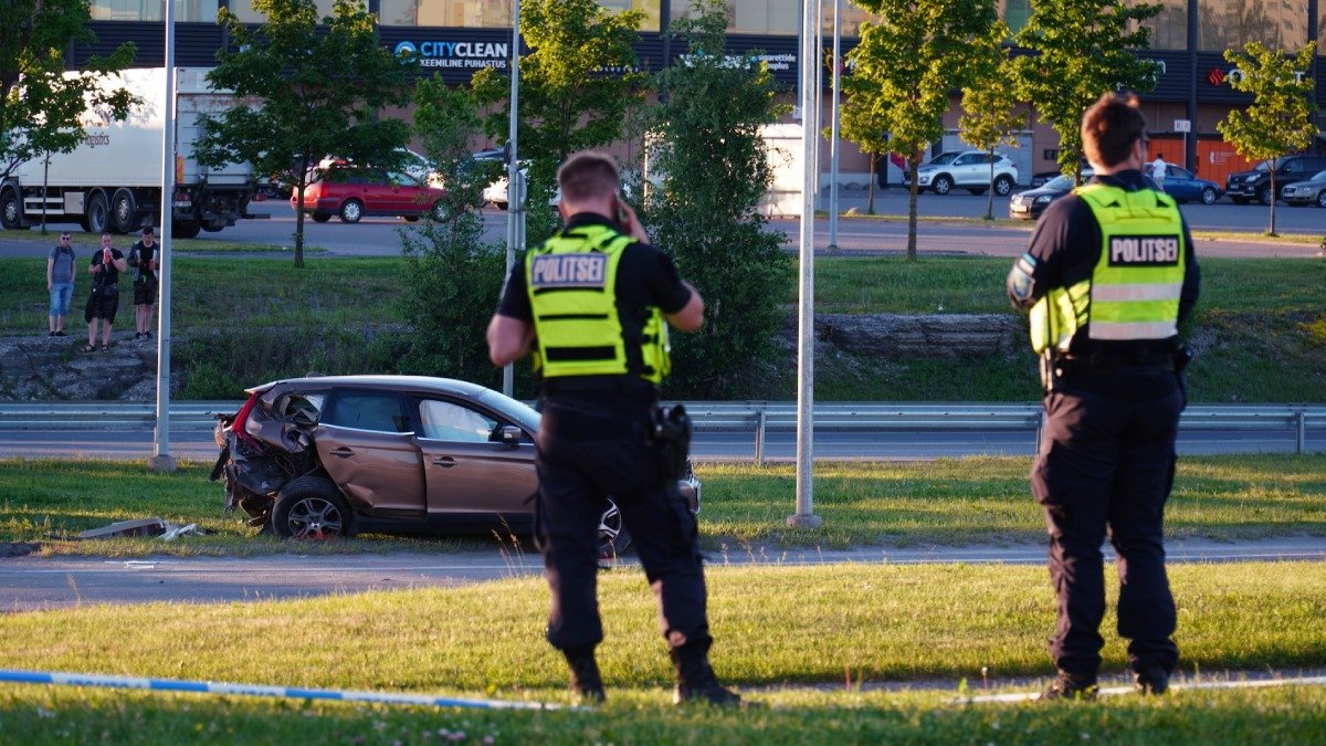 Två poliser står framför ett bilvrak
