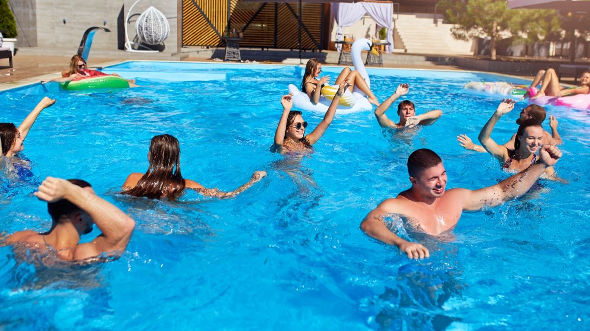 Ett gäng glada människor badar i pool utomhus.