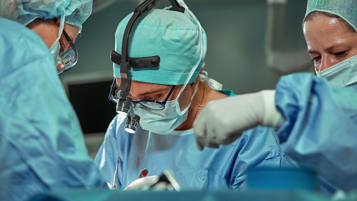 Kirurger i grönblå kläder under en operation