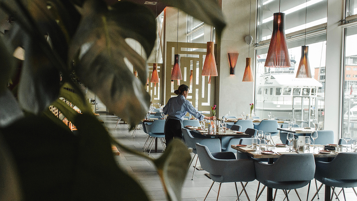 Servitör dukar bord på en restaurang.