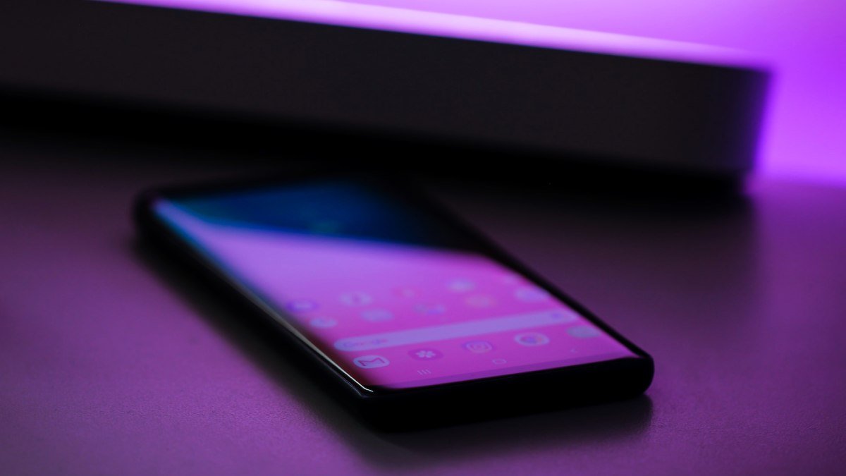 En smartphone på ett bord, lila ljus.