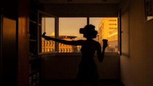 Kvinna spelar spel med VR-glasögon i siluett, fönster och stad bakom