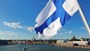 Finlands flagga vajar över vattnet i stadsmiljö, sommartid.