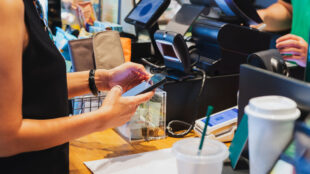 Kvinna betalar med mobilen på ett kafé.