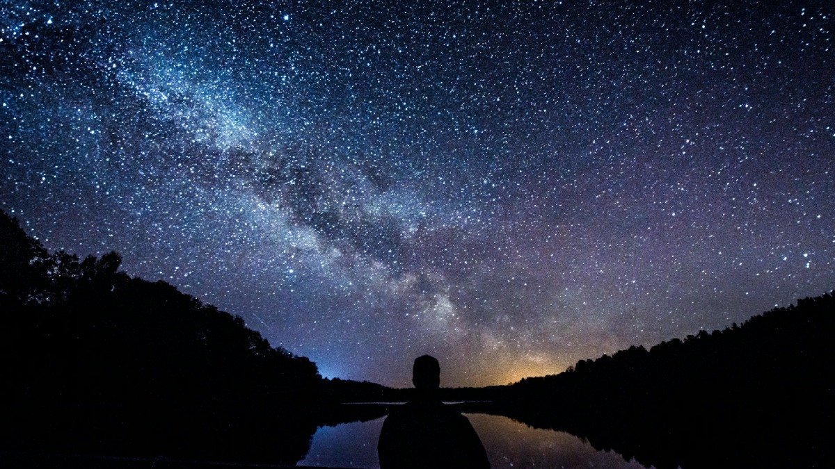 Stjärnhimmel med många stjärnor. Person i förgrunden. Natt.