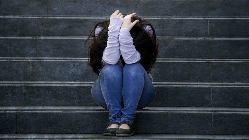 Ung kvinna sitter ensam i en trappa.