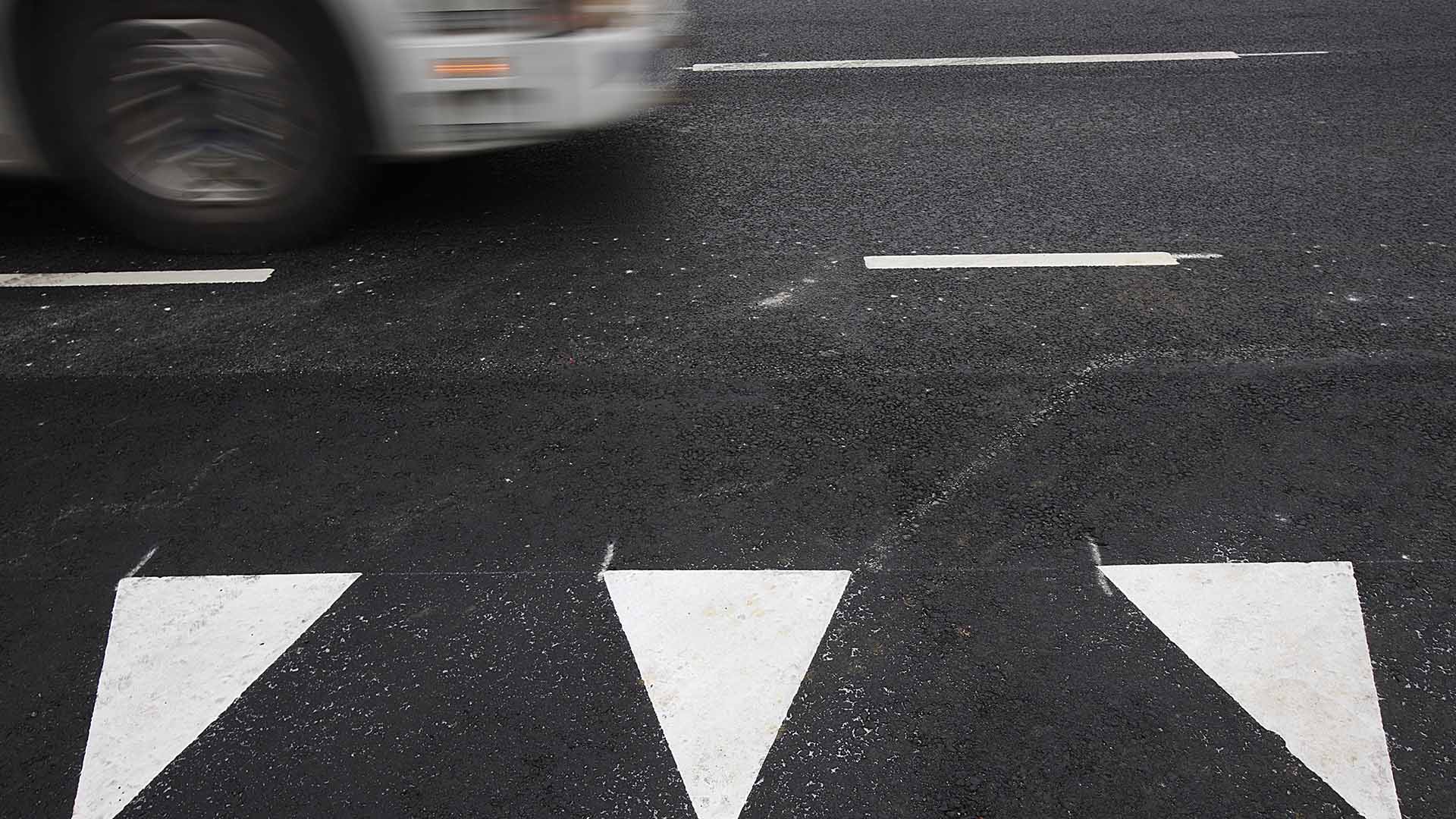 Triangelformade markering på en väg. I bakgrunden syns ett fordon.