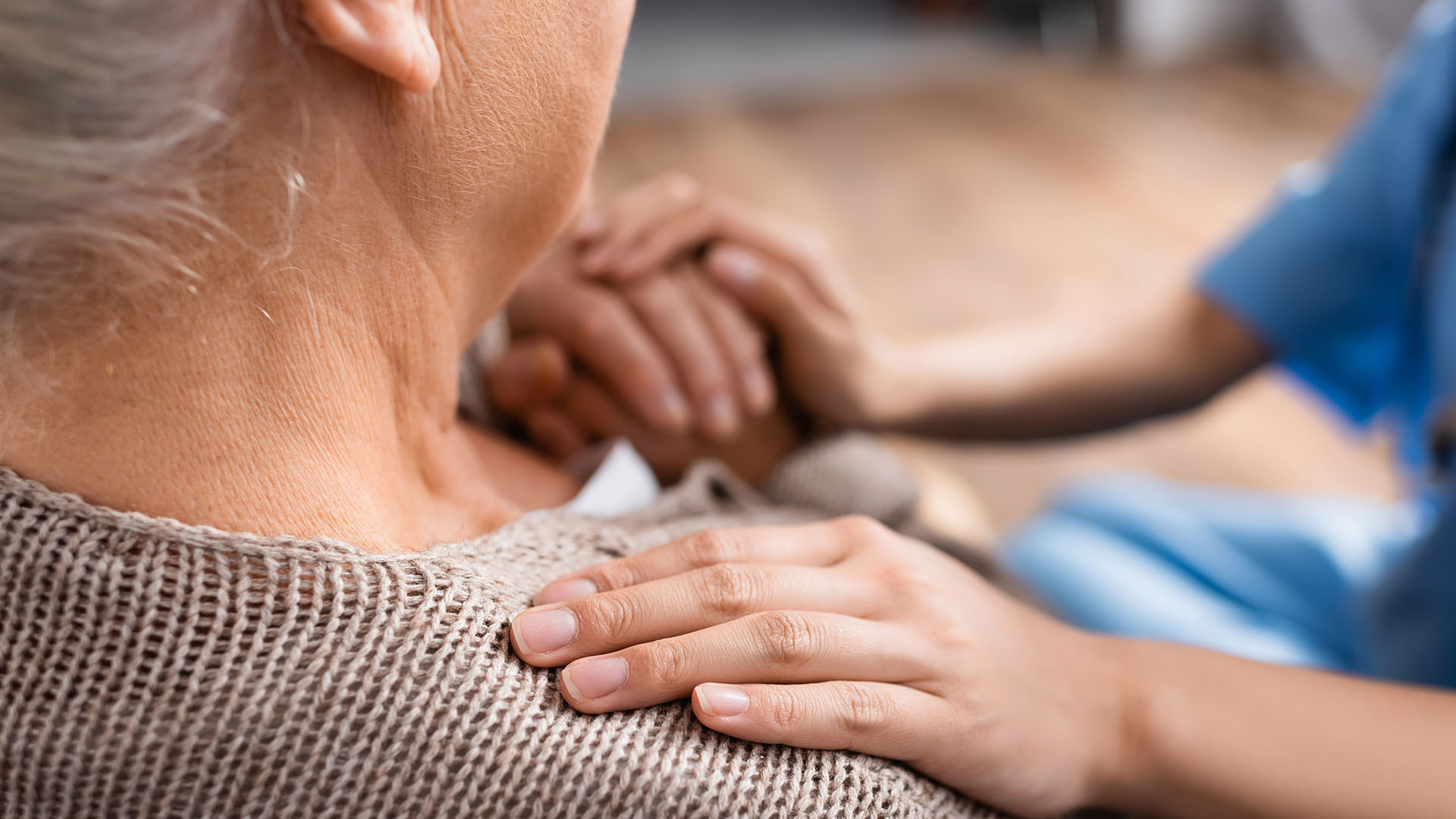 Kvinnlig personal håller äldre kvinnas hand.